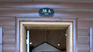 Une cabane en rondins avec une façade en bois, une chambre à coucher située en mezzanine sous un plafond en pente et une petite cuisine.