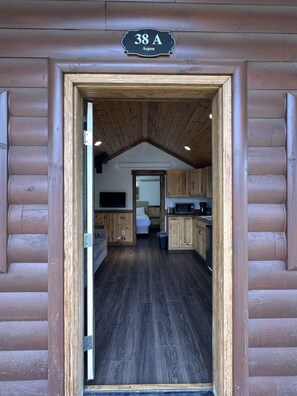 Eine Blockhütte mit Holzfassade, einem Schlafzimmer im Heuboden unter schrägem Dach und einer Küchenzeile.