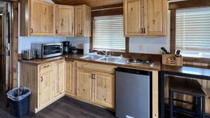 Une cuisine avec des meubles en bois, un lave-vaisselle en acier inoxydable et un plan de travail sur lequel se trouve une machine à café.