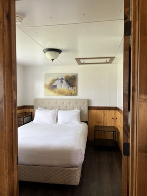 Ein Schlafzimmer mit einem Bett, einem Nachttisch, einem Gemälde und einer hölzernen Bank.