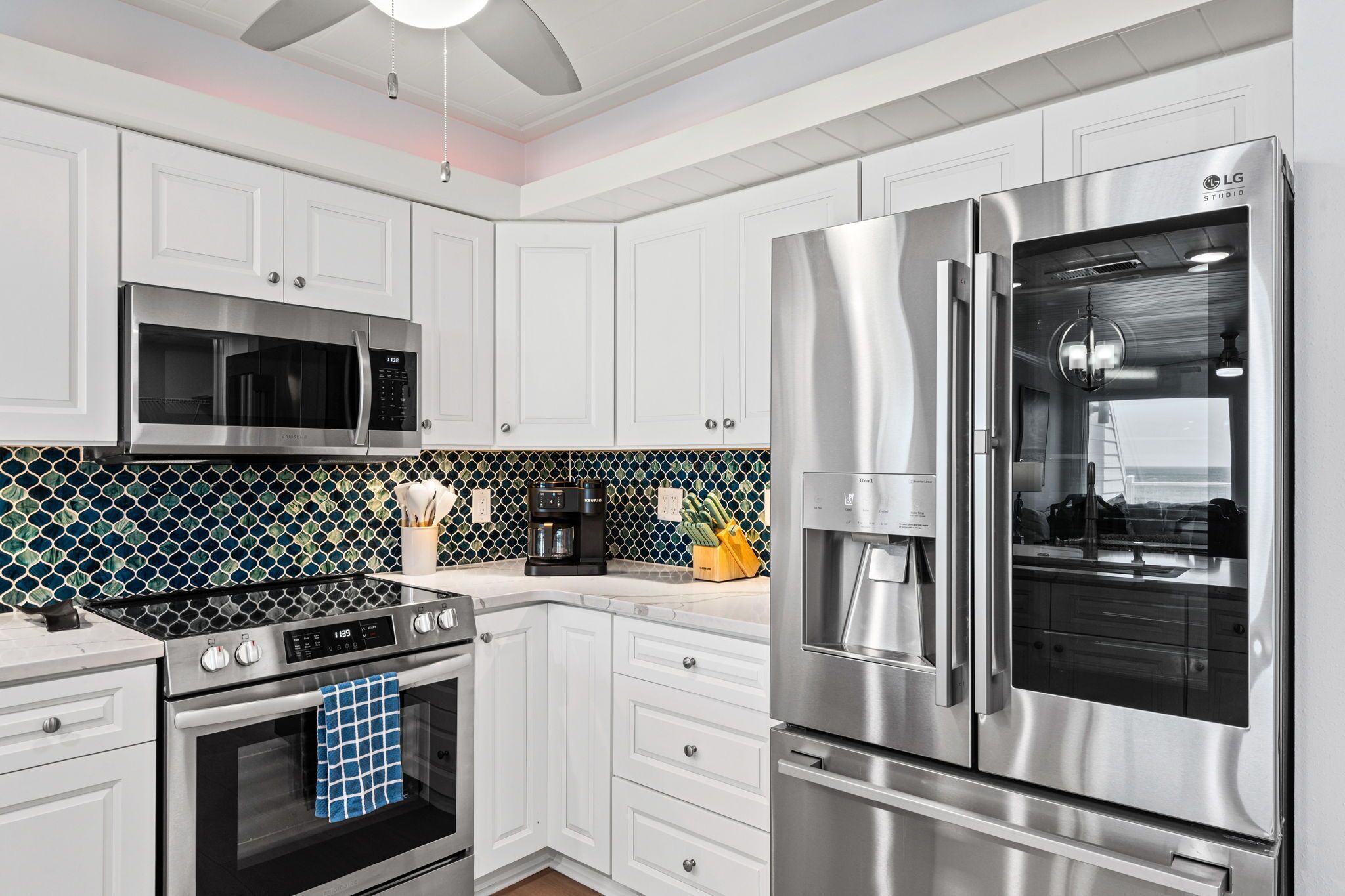 A modern kitchen with white cabinetry, stainless steel appliances, and a patterned backsplash.