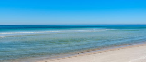 A beach with clear blue water and a sandy shore.