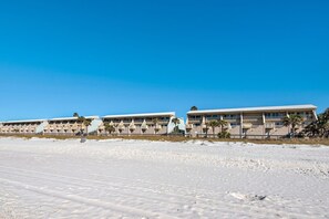 A beachfront hotel with multiple-story buildings, a sandy beach in the foreground, and clear blue skies. - 2BR Beachfront Townhome on PCB West End + Free Tix: Dolphin Cruise & More! (Panama City Beach)