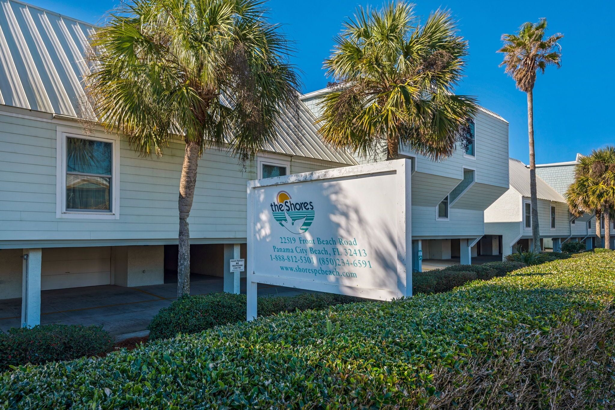 A hotel with a signboard displaying the name and contact information.