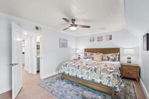 A bedroom with a bed, nightstands, a ceiling fan, and a door leading to another room. - 2BR Beachfront Townhome on PCB West End + Free Tix: Dolphin Cruise & More! (Panama City Beach)