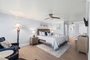 A bedroom with a bed, bedside tables, a chair, a lamp, a ceiling fan, and a door. - 2BR Beachfront Townhome on PCB West End + Free Tix: Dolphin Cruise & More! (Panama City Beach)