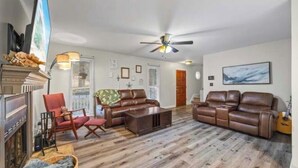 A living room with a fireplace, leather sofas, a coffee table, and a ceiling fan.
