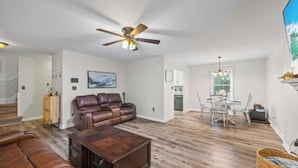 A spacious living area with a ceiling fan, a leather sofa, a coffee table, and a dining area with a table and chairs.