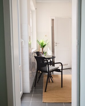 A small dining area with a table and chairs, a potted plant, and a door in the background. - Bright & Modern 2 Bedroom Apartment in Ixelles (Ixelles)
