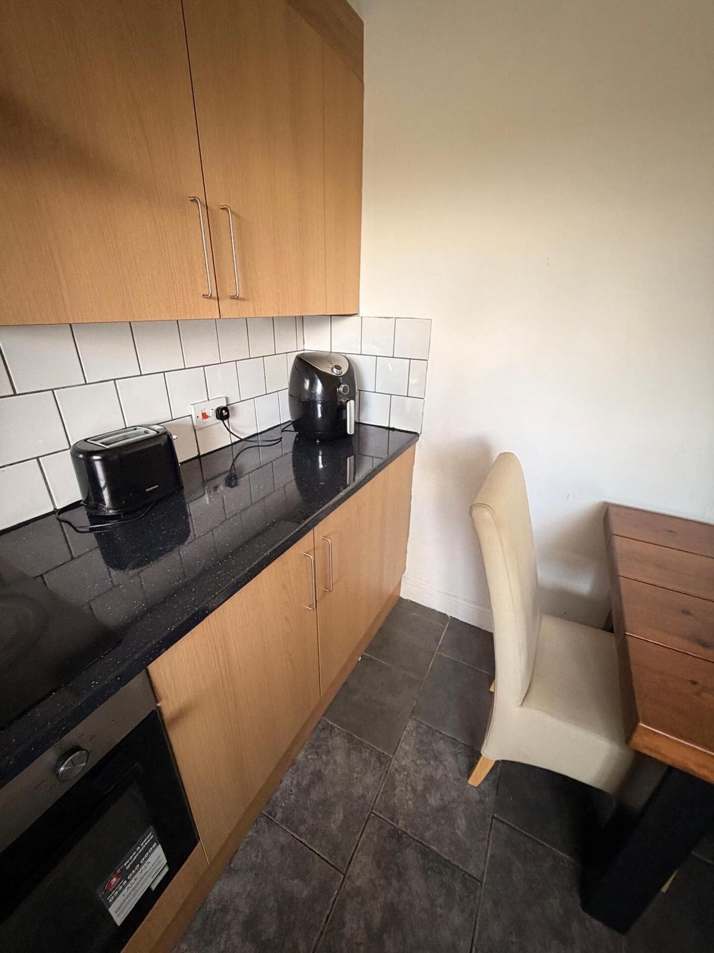 A kitchen with wooden cabinets, a black countertop, a toaster, and a kettle.