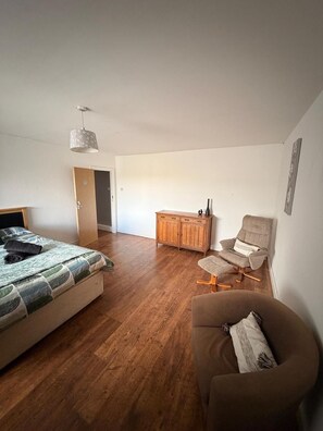 Ein Schlafzimmer mit einem Bett, einem Sessel, einem Schrank und einer Pendelleuchte.