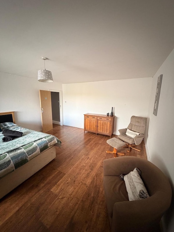 A bedroom with a bed, a chair, a cabinet, and a hanging light fixture.
