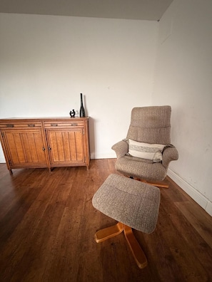 A wooden cabinet with drawers and a chair with a footrest.