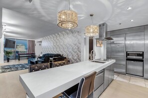 A modern kitchen with a large island, stainless steel appliances, and a marble backsplash. - Remodeled Corner Suite - Wraparound Balcony & Panoramic Strip Views (Las Vegas)