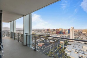 Un balcon offrant une vue sur la ville, avec un ciel dégagé et des bâtiments situés au loin.