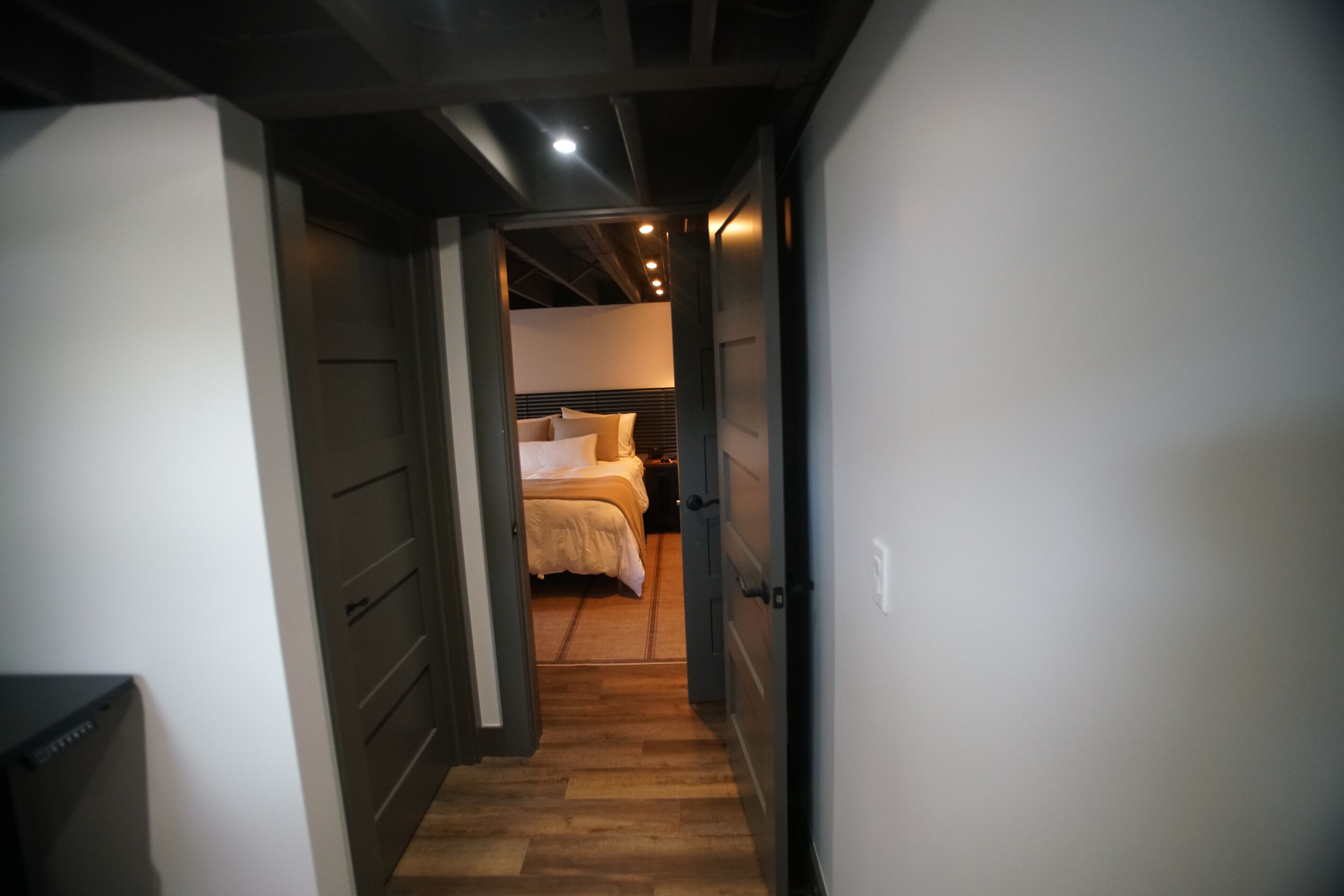 A narrow hallway leading to a bedroom with a bed and nightstands.