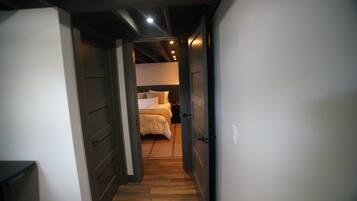 A narrow hallway leading to a bedroom with a bed and nightstands.