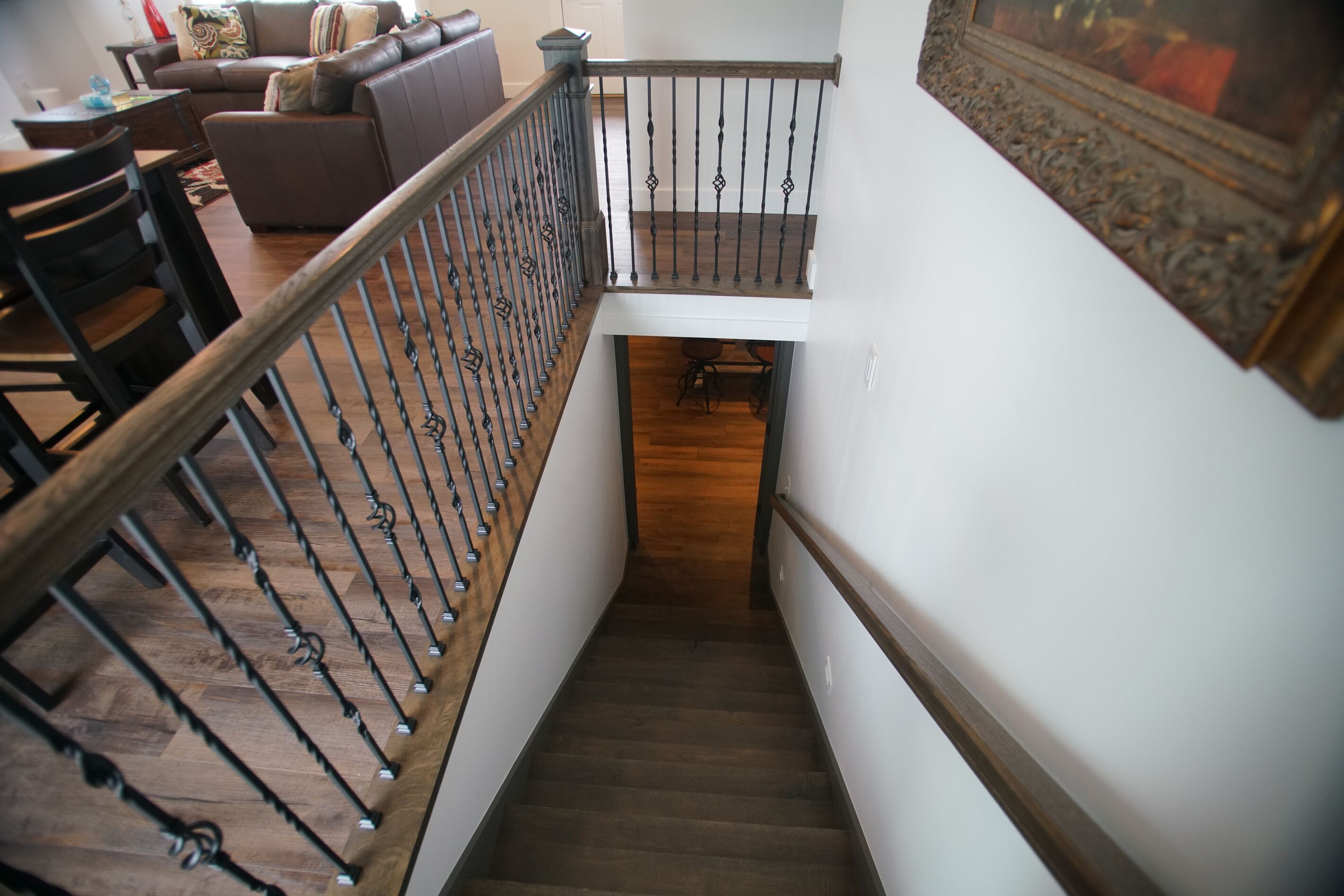 Eine Treppe mit einem hölzernen Geländer und Metallspindeln, die zu einer unteren Ebene führt.