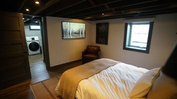 A bedroom with a bed, a chair, a painting, and a window.