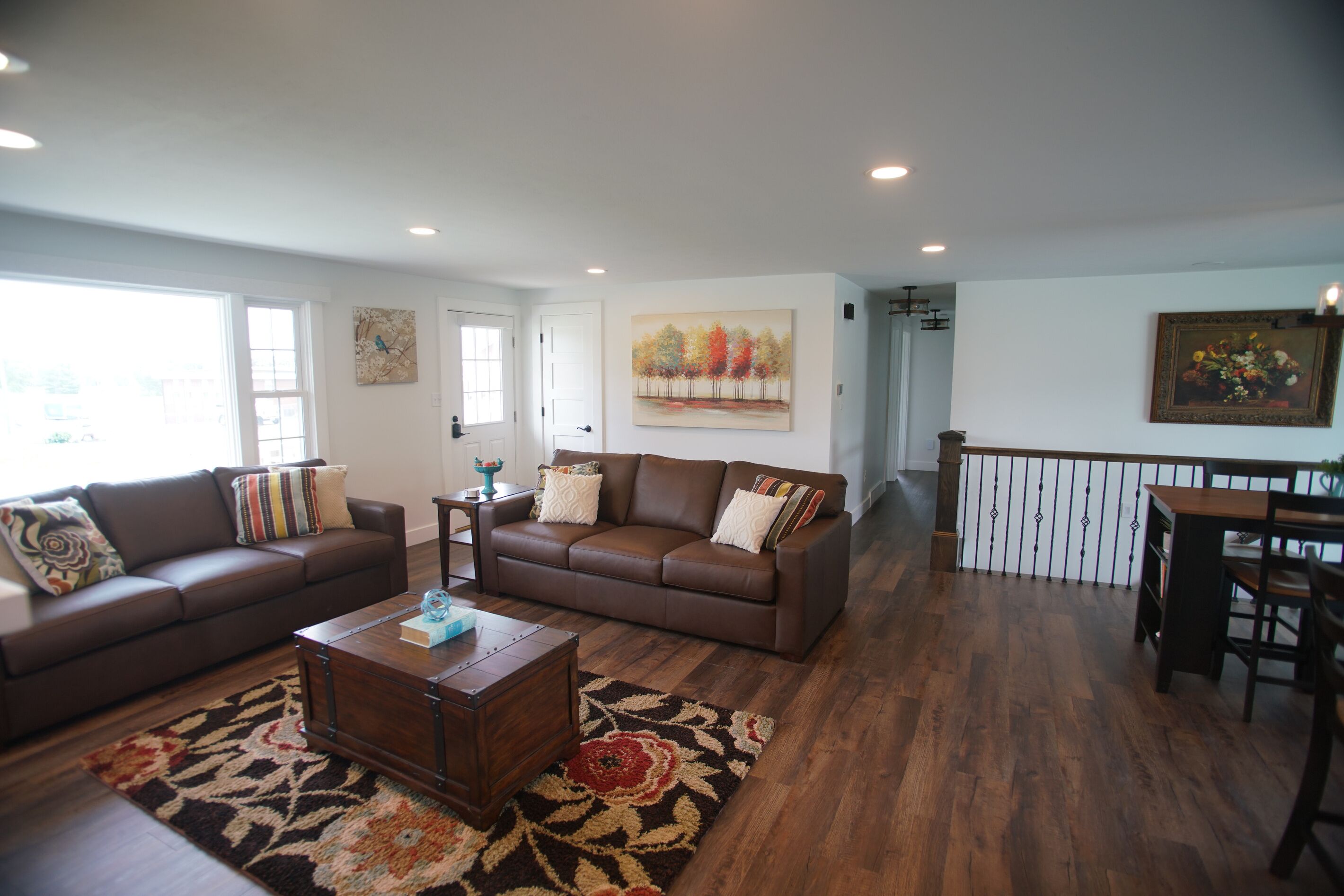 A spacious living room with two brown leather sofas, a wooden coffee table, and a patterned rug.