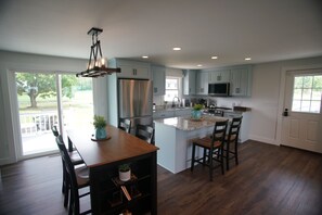 A spacious kitchen with a central island, stainless steel appliances, and light blue cabinetry. - Black, White, & Barn w/ Hot Tub & Fire Pit (Fredericktown)