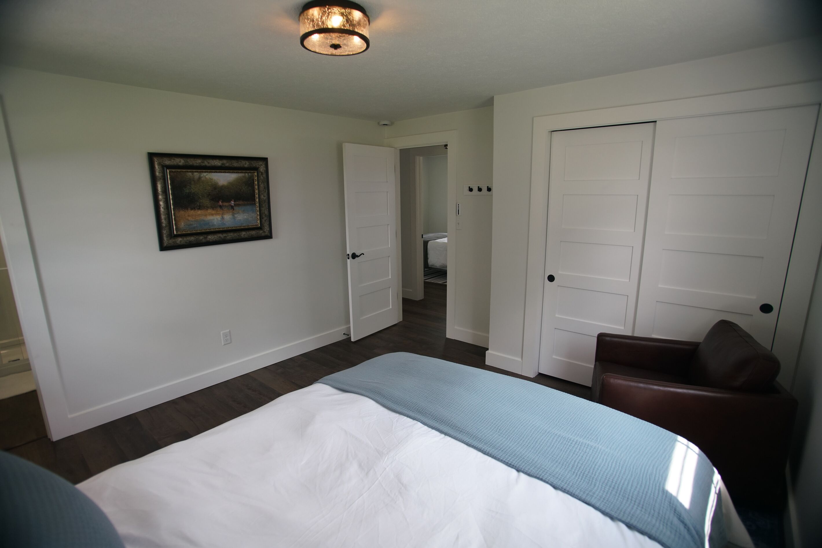 Une chambre d’hôtel avec un lit, un tableau, une porte et une chaise.