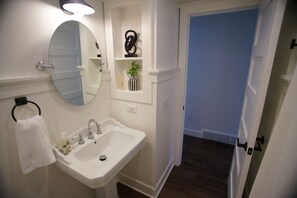 A bathroom with a white sink, a round mirror, and a towel rack. - Black, White, & Barn w/ Hot Tub & Fire Pit (Fredericktown)
