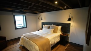 Ein Schlafzimmer mit einem Bett, Nachttischlampen, einem Fenster und einer Deckenleuchte.