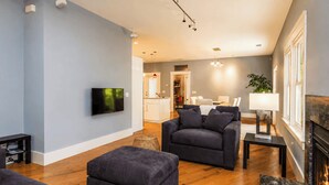 Ein modernes Wohnzimmer mit einer Couch, einem Hocker und einem Flachbildfernseher.