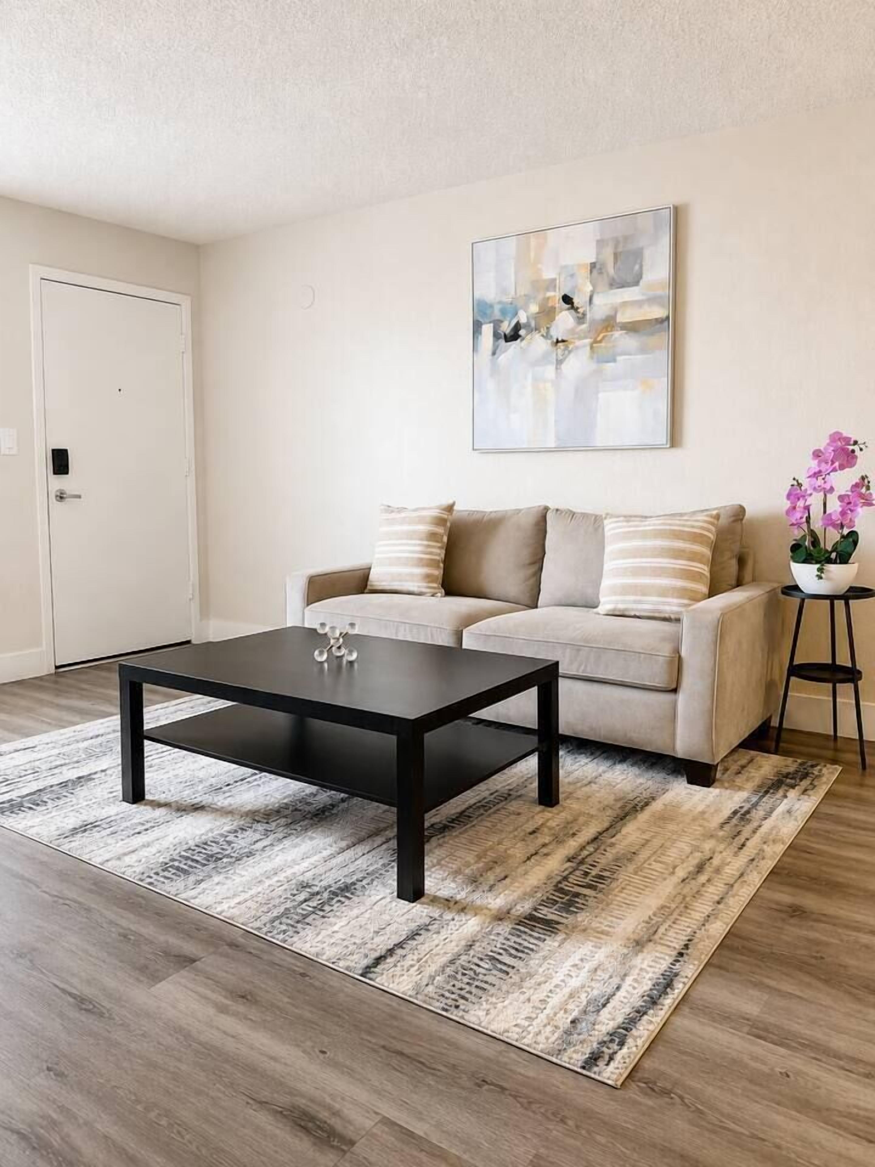A living room with a sofa, coffee table, and a painting on the wall.
