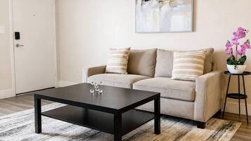 A living room with a sofa, coffee table, and a painting on the wall.