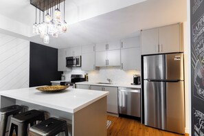 A modern kitchen with a central island, stainless steel appliances, and a chalkboard wall.
