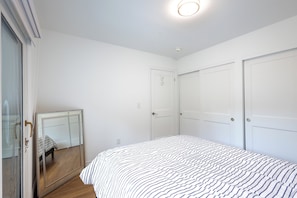 A bedroom with a bed, a mirror, and two doors.
