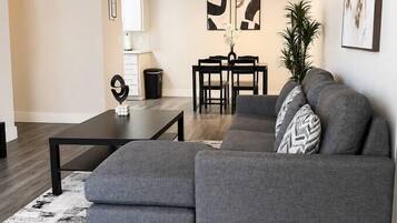 A modern living room with a grey sectional sofa, a black coffee table, and a white rug.