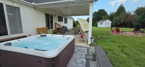 Ein Garten mit Whirlpool, Gartenmöbeln und einer Terrassenfläche.