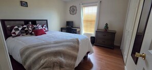 Ein Schlafzimmer mit einem Bett, einem Schreibtisch, einer Kommode und einer kleinen Weihnachtstanne.