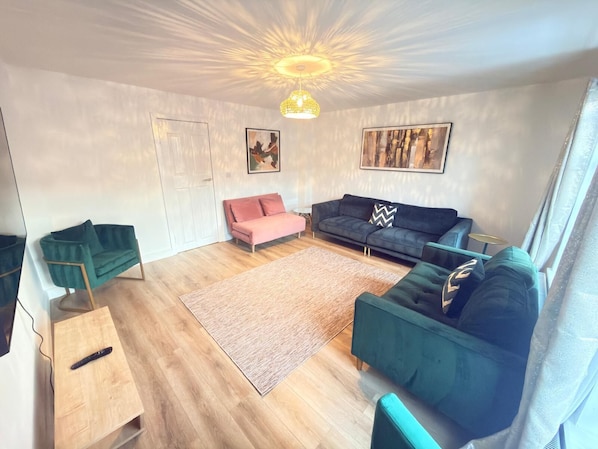 Un salon moderne avec un plancher en bois, deux canapés, une table basse et un luminaire suspendu au plafond.