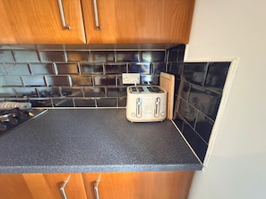 A kitchen with a black countertop, wooden cabinets, and a toaster.