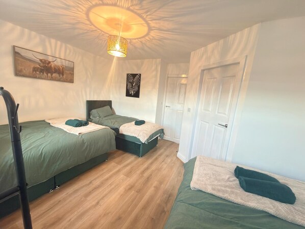 A room with two beds, a ceiling light fixture, and a door.