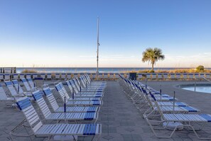 A beachside lounge area with rows of sun loungers and a palm tree. - 3BR Edgewater Condo Pools, Golf, Tennis & Private Beach Access! (Panama City Beach)