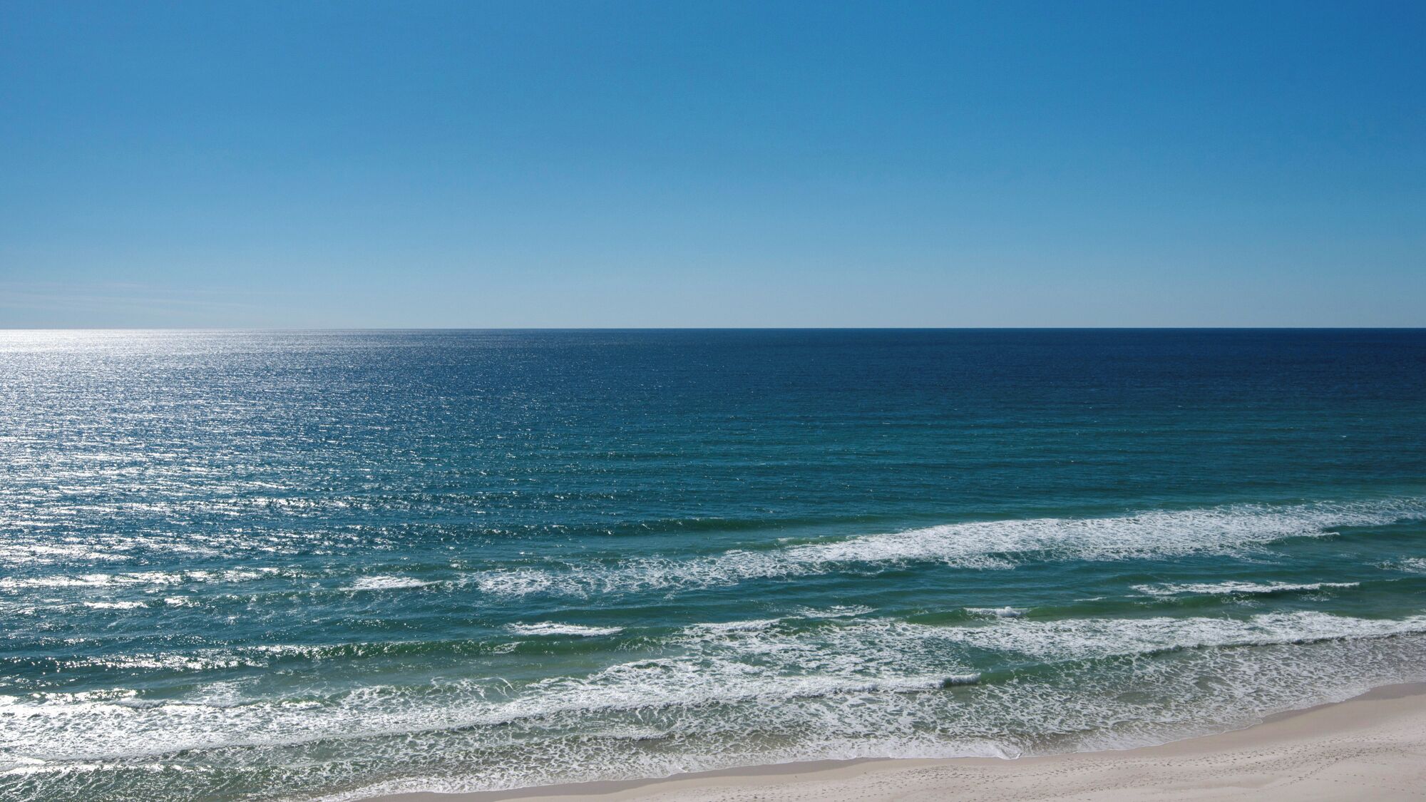 A beach with clear blue water and a sandy shore.
