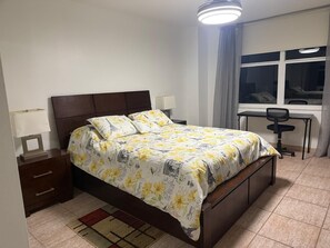 Een slaapkamer met een bed, nachtkastjes, een bureau en een stoel.