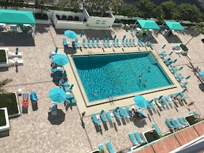 A rooftop pool area with multiple sun loungers and umbrellas, surrounded by a tiled deck. - Cozy 2bedroom 2 bath apartment on the beach in Hollywood with direct ocean views (Hollywood)