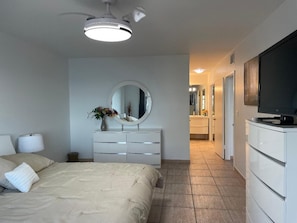 A bedroom with a bed, a dresser, a television, and a mirror. - Cozy 2bedroom 2 bath apartment on the beach in Hollywood with direct ocean views (Hollywood)