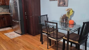 Comedor con mesa de vidrio, dos sillas, un jarrón con flores secas y una decoración de calabaza.