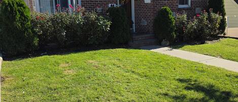A residential house with a brick exterior, a front porch, and a well-maintained lawn.