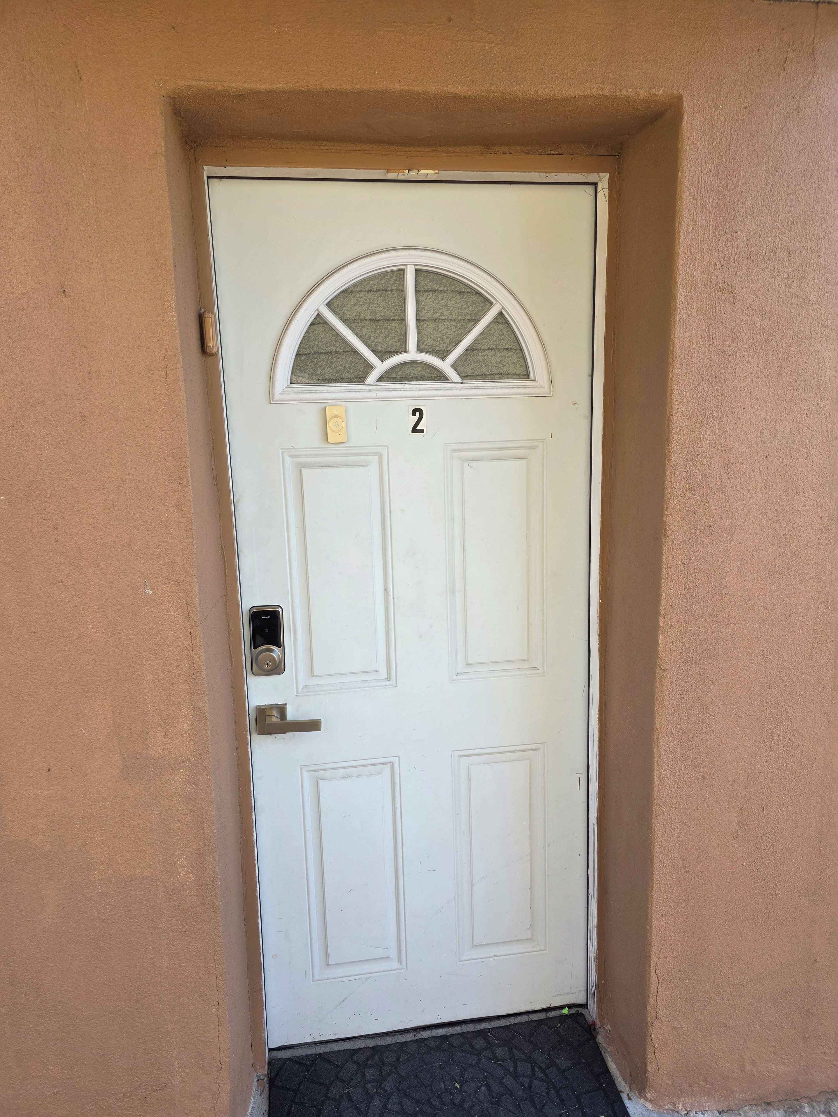 A white door with a number '2' above it, a small window with a glass top, and a doorbell.