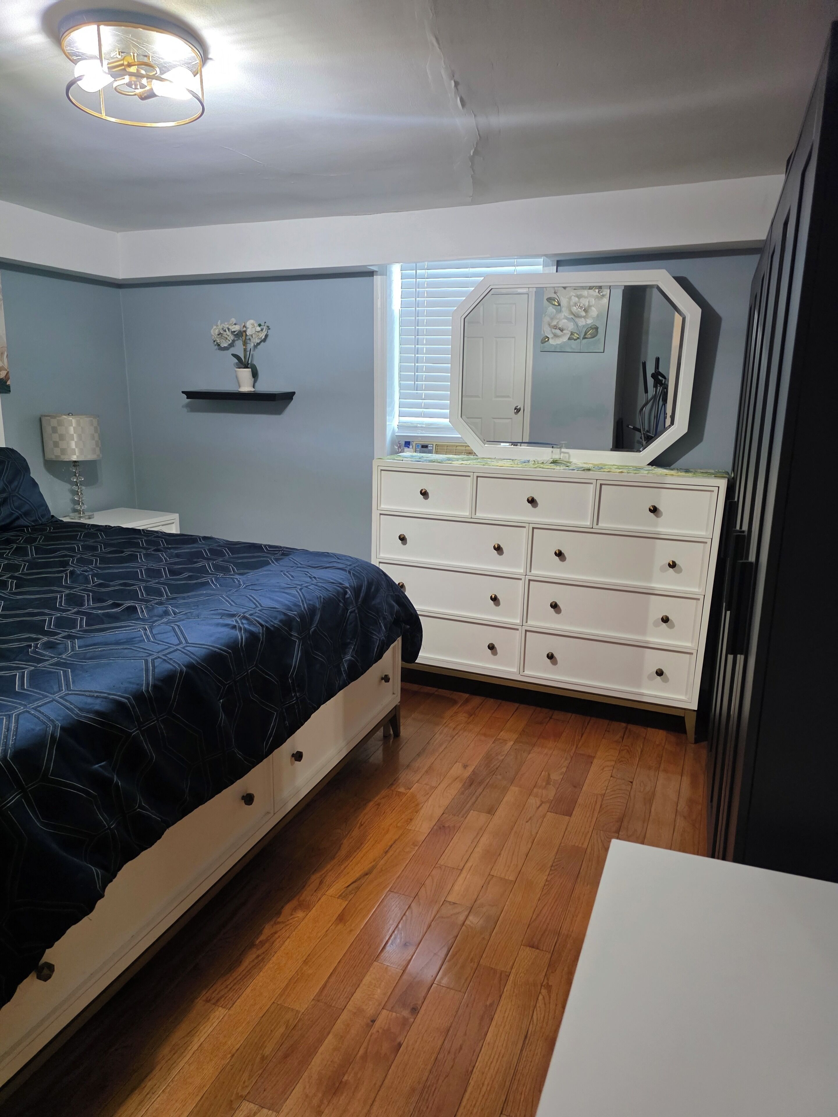 Una camera da letto con un letto, una cassettiera e una ventola a soffitto.