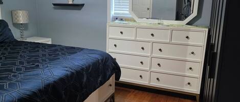 A bedroom with a bed, dresser, and a ceiling fan.