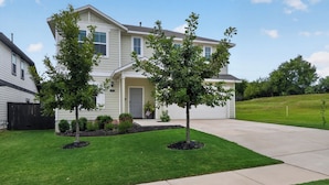 A two-story house with a front yard, a driveway, and a mailbox.